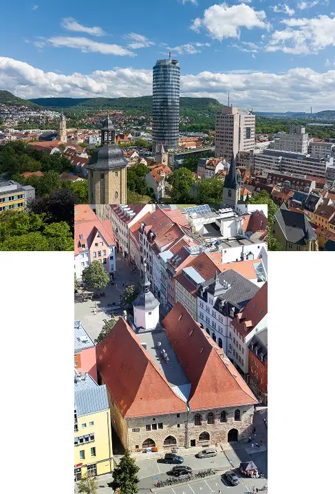 Panoramablick auf eine deutsche Stadt mit einer Mischung aus historischer und moderner Architektur; im Vordergrund ist ein mittelalterliches Gebäude mit rotem Ziegeldach zu sehen, dahinter ragen moderne Hochhäuser und Kirchtürme in den Himmel, eingebettet in eine grüne Hügellandschaft.