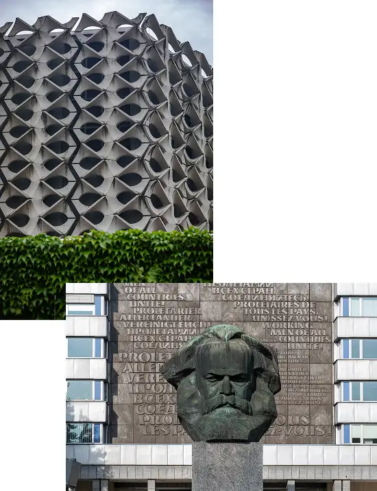 Fassade mit geometrisch-skulpturaler Betonstruktur über einer grünen Hecke, darunter monumentale Karl-Marx-Büste vor Plattenbau mit multilinguale Inschrift