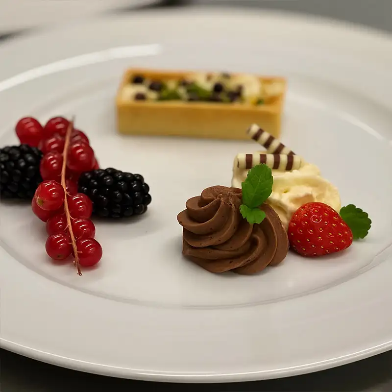 Dessertteller mit feinen Komponenten auf weißem Porzellan angerichtet