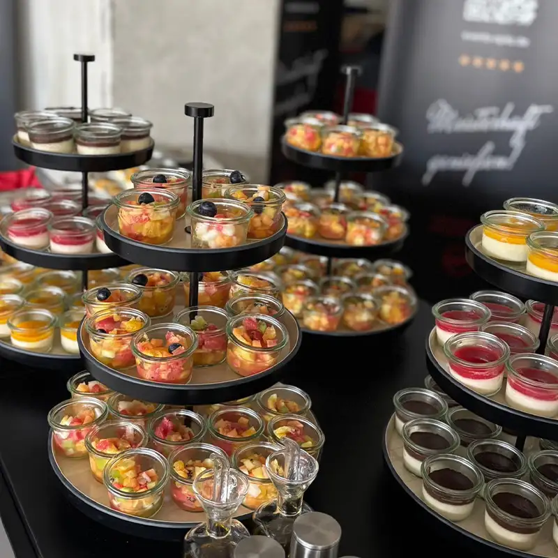 Verschiedenste Desserts und Obstsalate in kleinen Gläsern auf mehreren Etageren stilvoll angerichtet