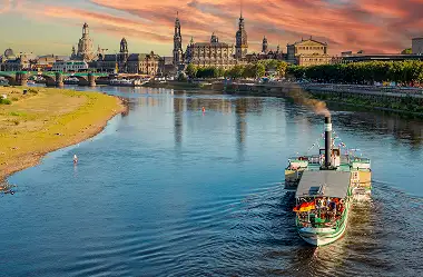 Historisches Dampfschiff auf der Elbe vor der barocken Altstadtkulisse von Dresden bei dramatischem Sonnenuntergang